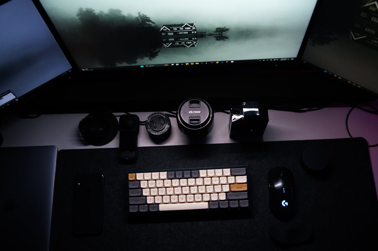 Minimalist work from home setup with triple monitors, keyboard, and tech accessories.