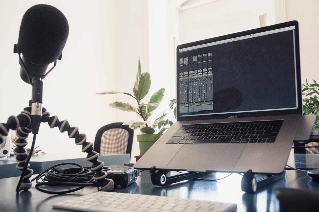 A detailed studio setup featuring a laptop and microphone on a desk for audio production.